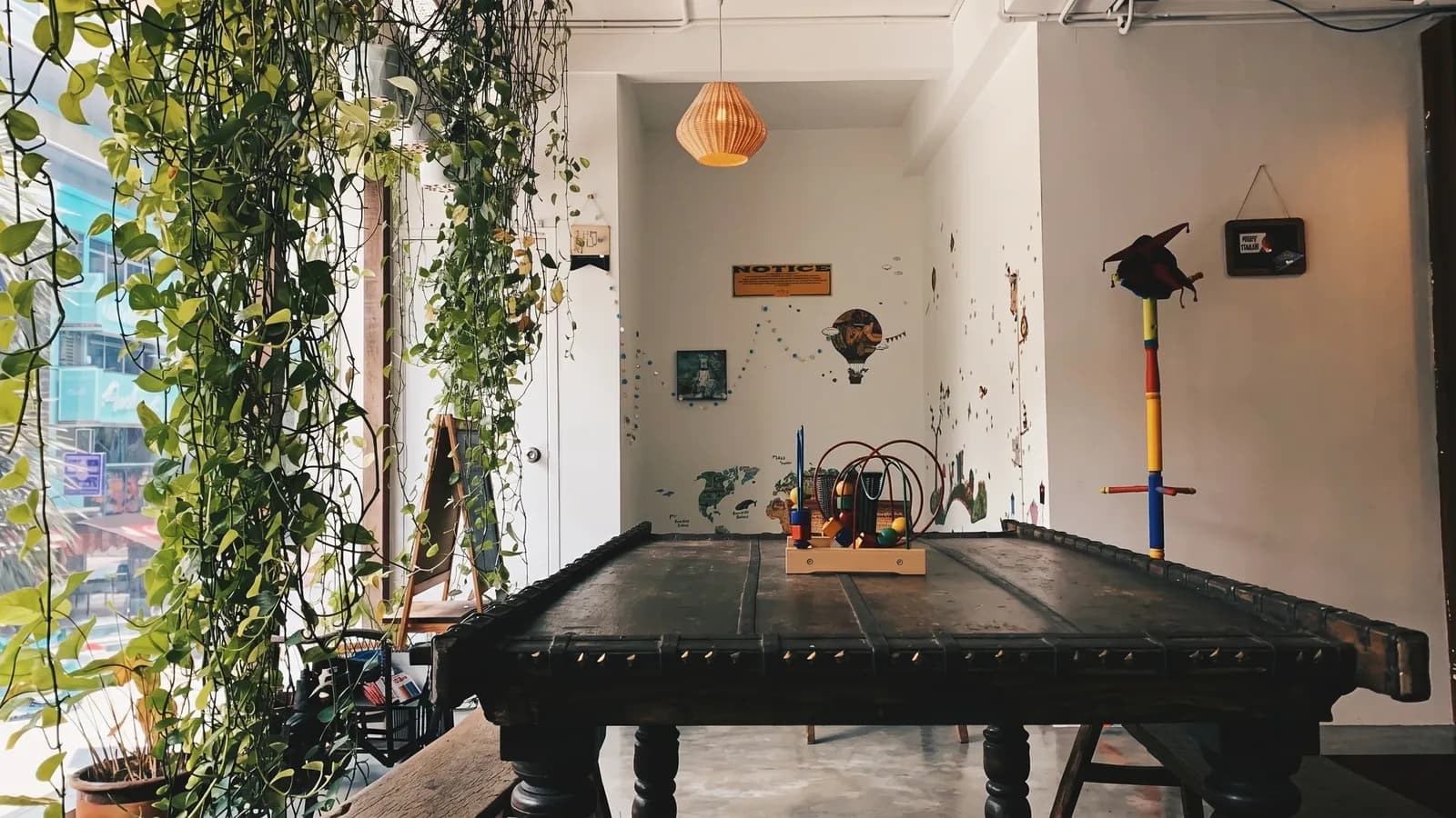 The common room at The Mind Faculty, cascading indoor plants trailing beside a window in soft daylight